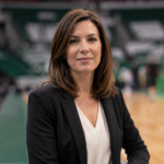 Kathleen Nimmo Lynch inspired professional woman standing inside a basketball arena with a blurred court background